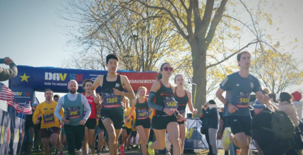 Runners participating in a marathon race, captured against a backdrop of trees and a clear sky.